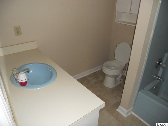 Bathroom with blue sink and toilet, off-white counter, tan walls, and a light blue bathtub.