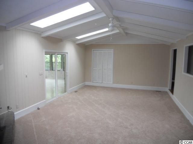 Empty room with beige carpet, tan walls, white trim, and skylights in the ceiling.