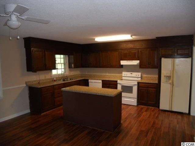 Kitchen with dark brown cabinets, light countertops, white appliances, and wood-look flooring.