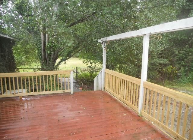 Wooden deck with red stain and light wood railings, leading to a grassy area.