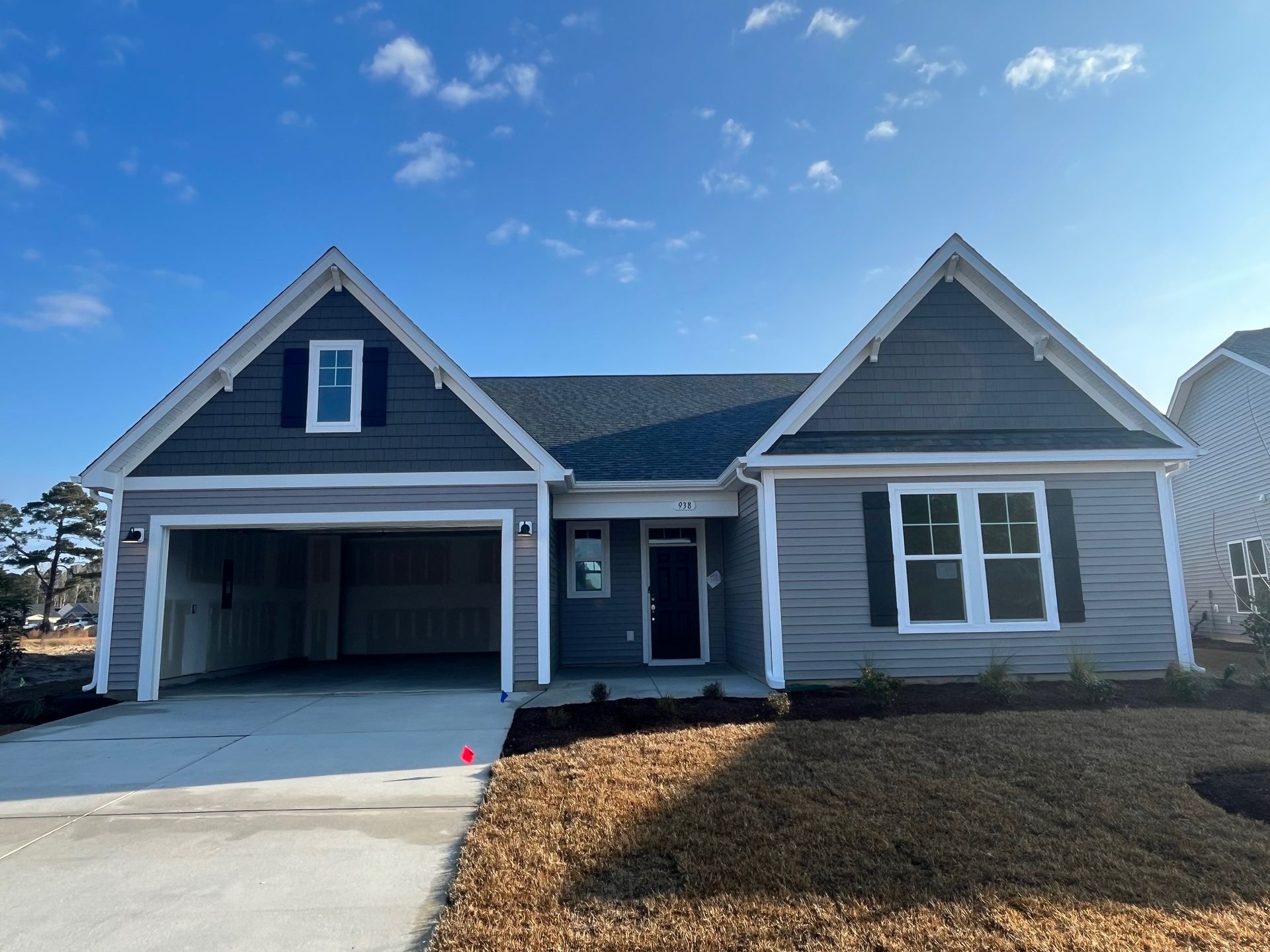 Gray house with a two-car garage under a blue sky, new construction.