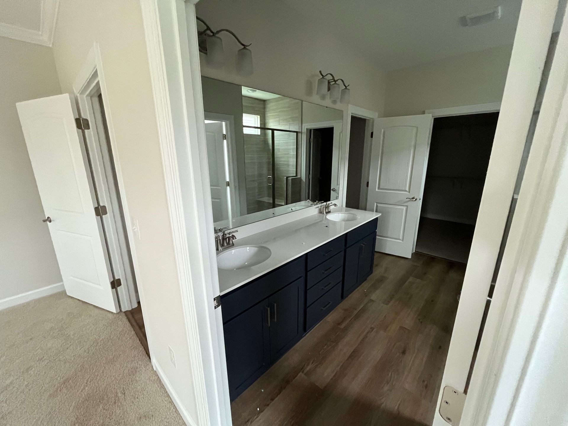 Bathroom with blue vanity, white countertop, large mirror, and two doors.