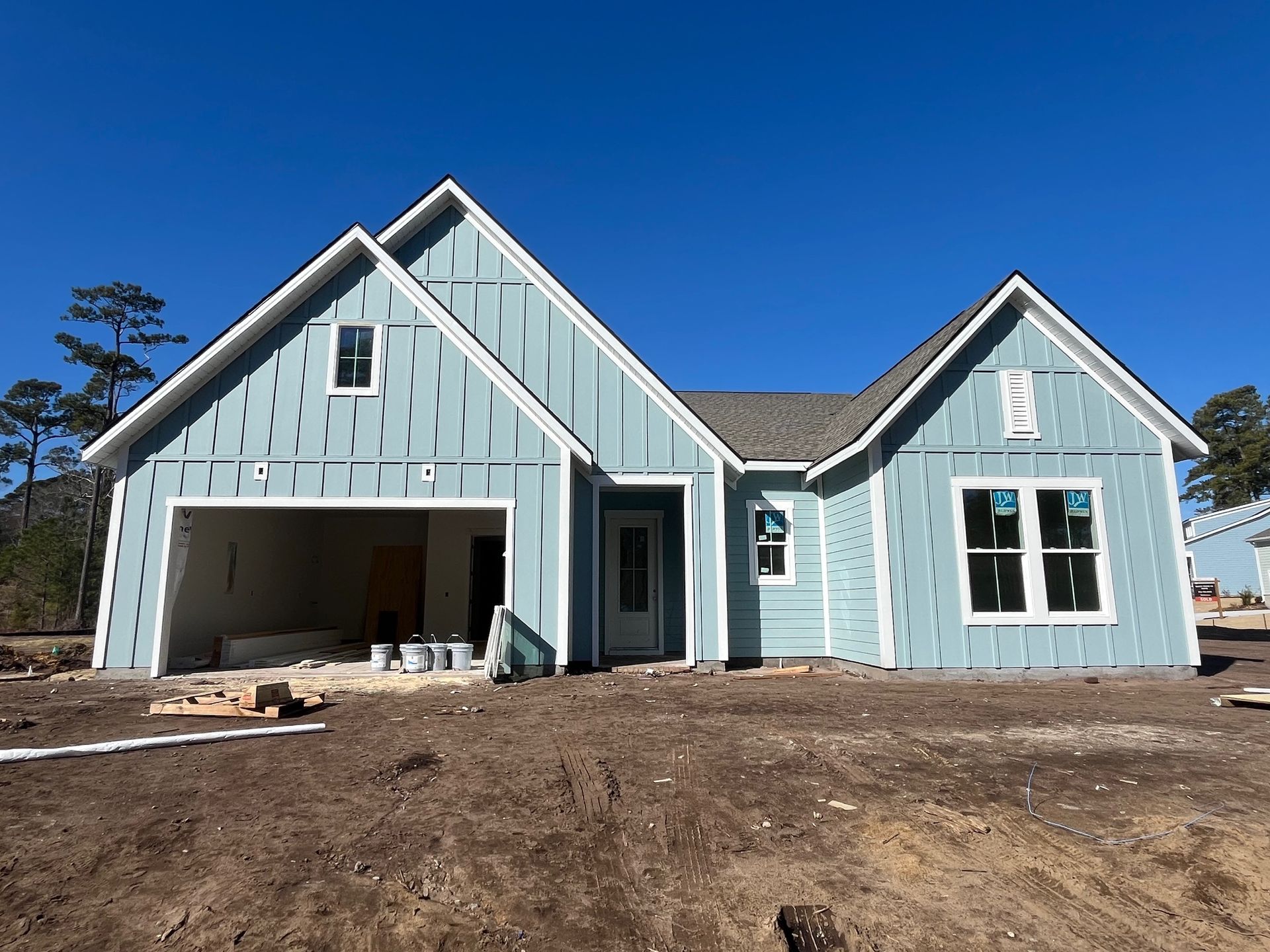 New light blue house under construction with white trim and a garage.