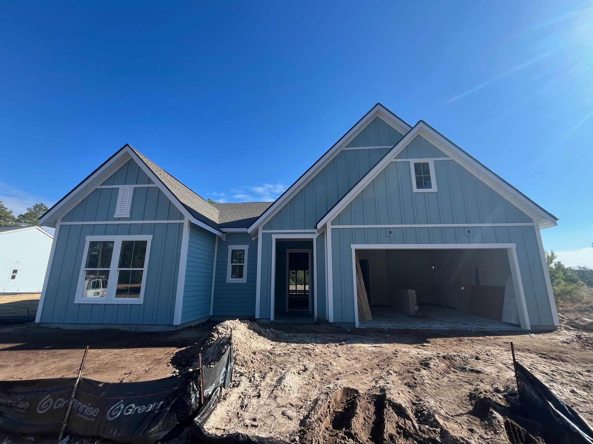 New light blue house under construction with a clear blue sky.