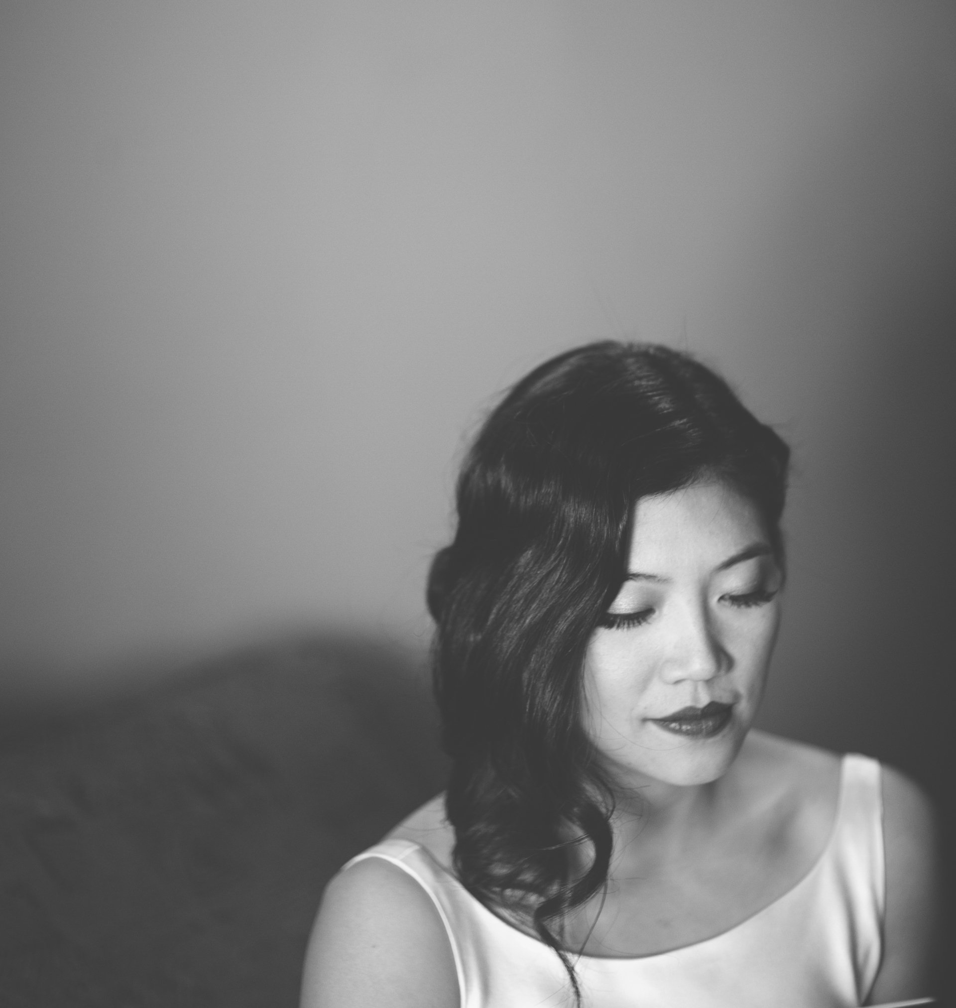 A black and white photo of a woman in a white dress looking down.