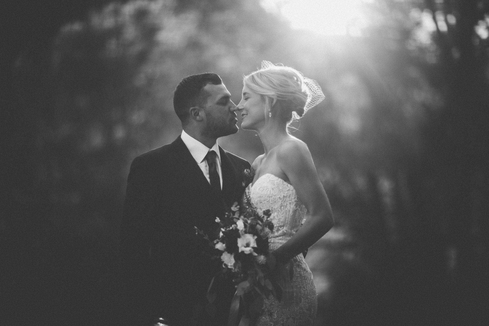 A bride and groom are kissing in a black and white photo.