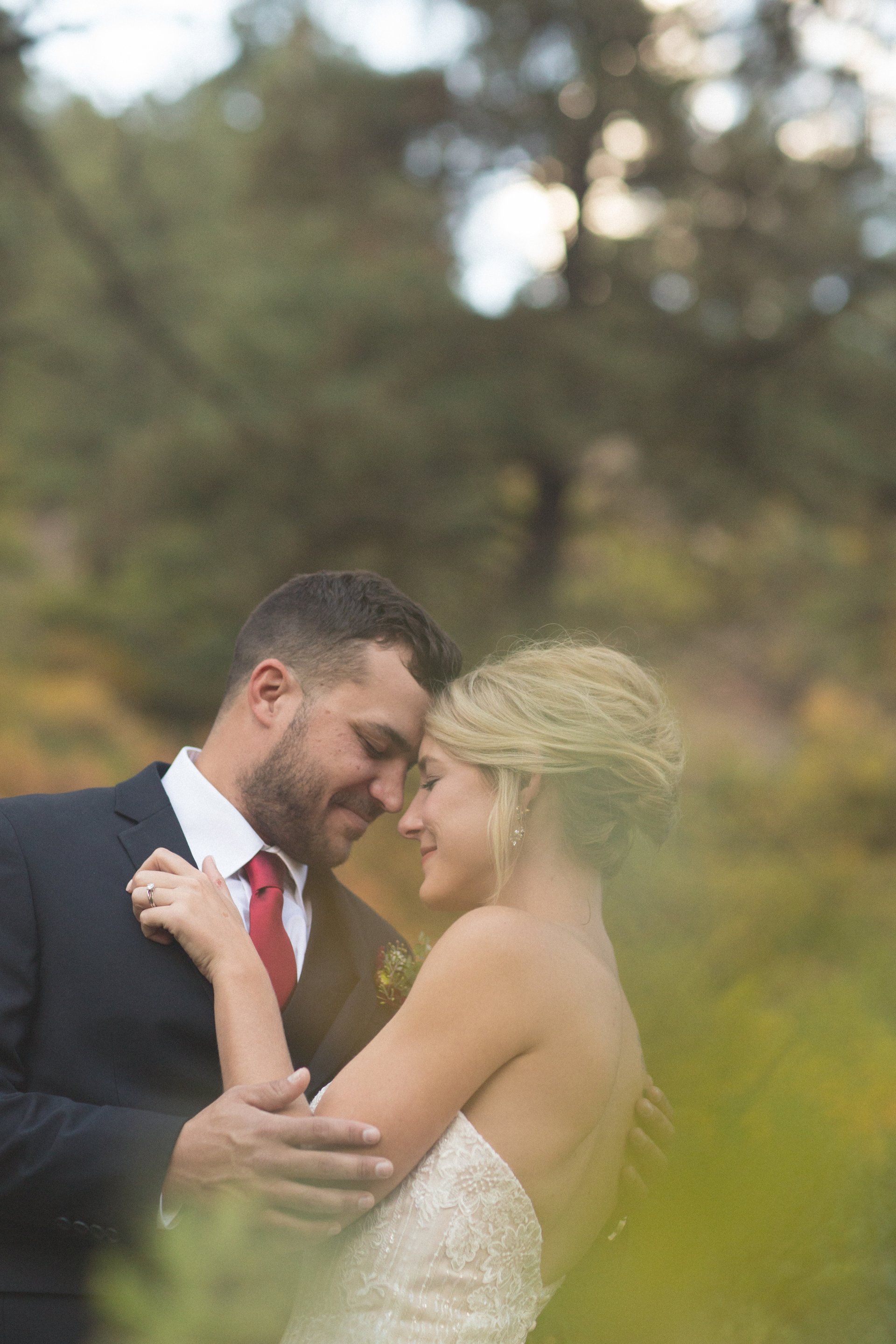 A bride and groom are looking at each other in a field.