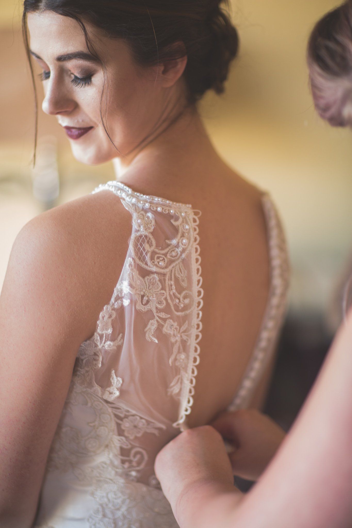 A woman is helping a bride with her wedding dress.