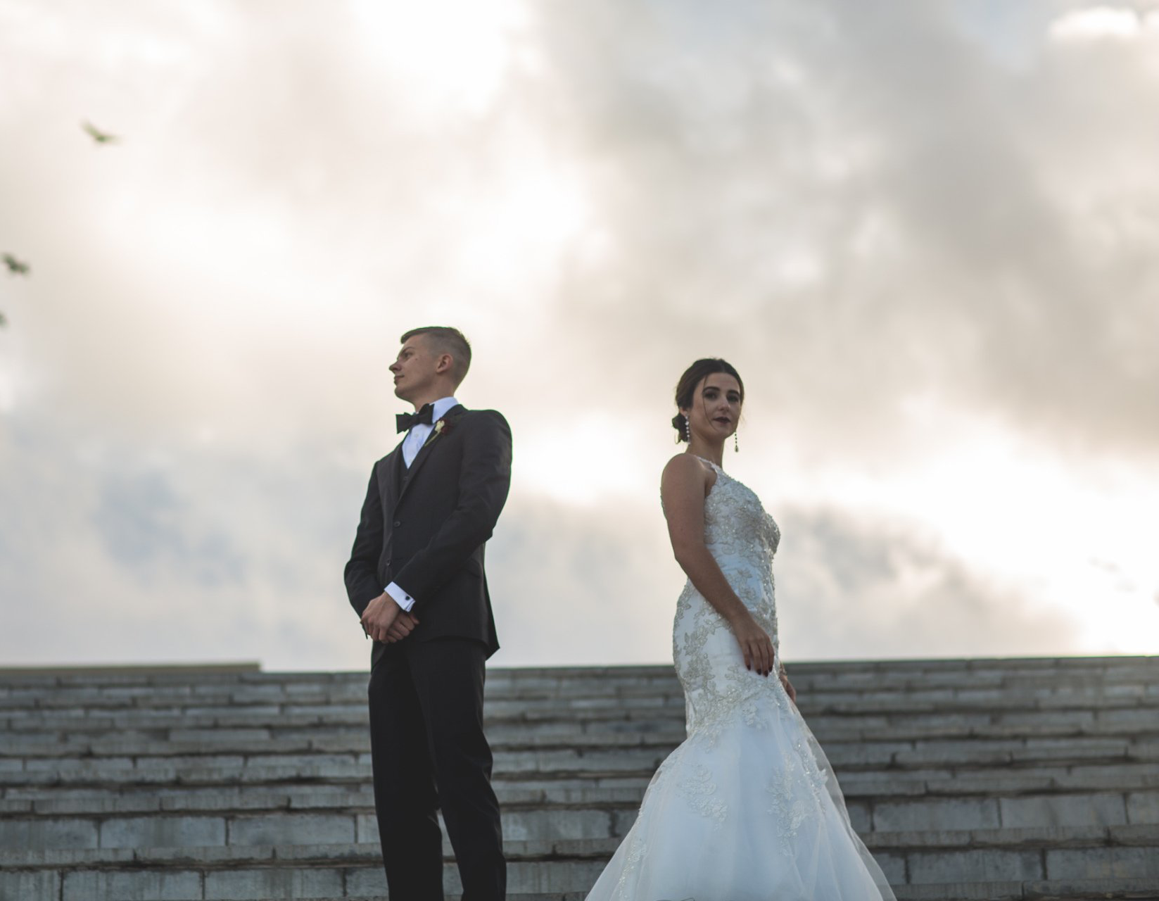 A bride and groom are standing next to each other on a set of stairs.