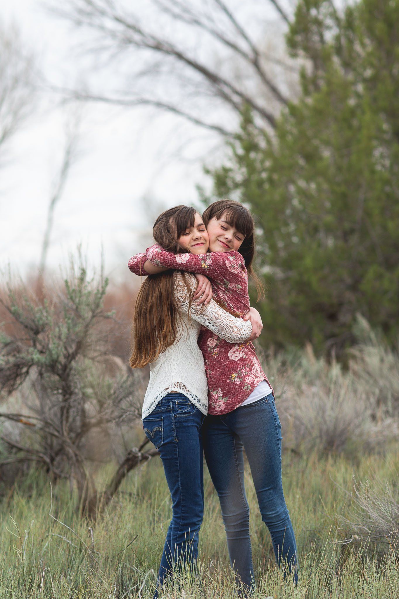 Two women are hugging each other in a field.