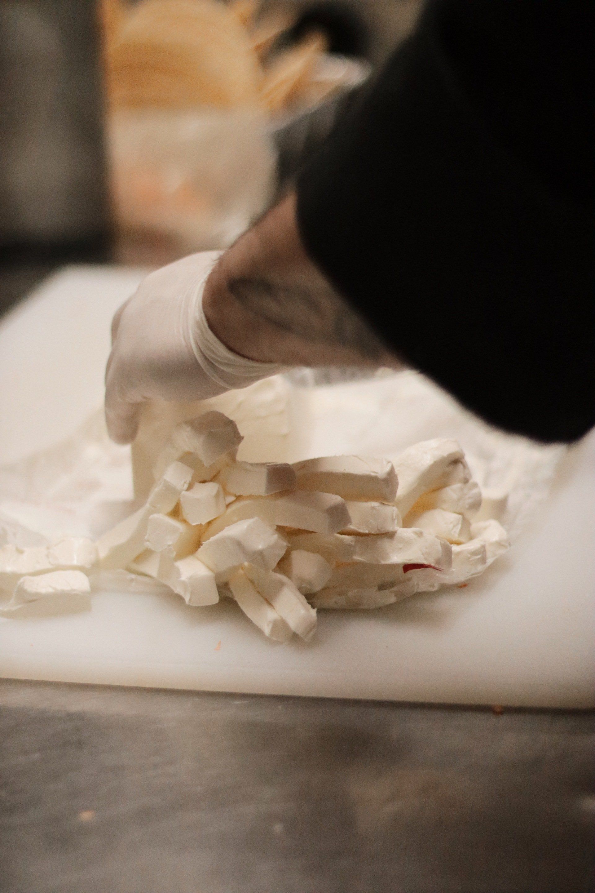 A person is cutting a piece of cheese on a cutting board.