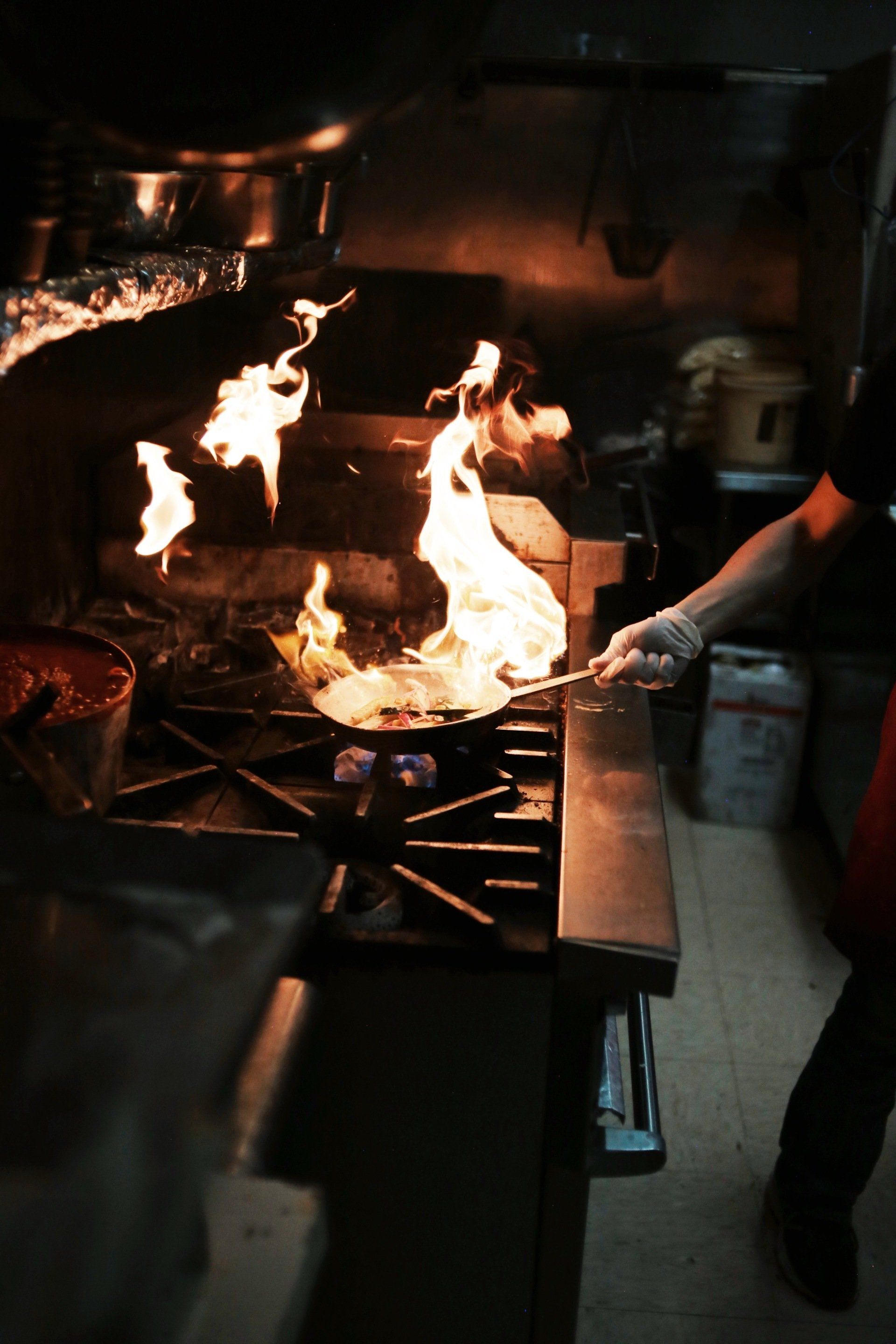 A person is cooking on a stove with flames coming out of it