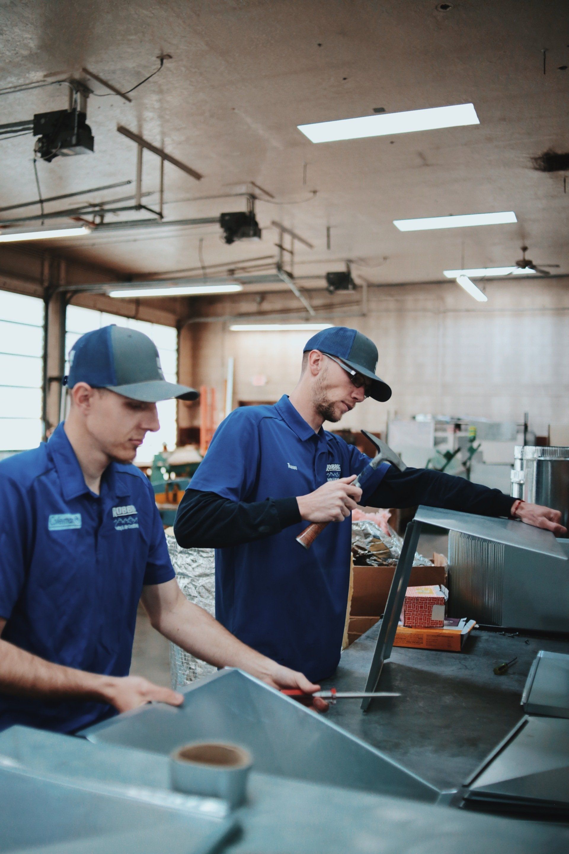 Two men are working on a piece of metal in a factory.