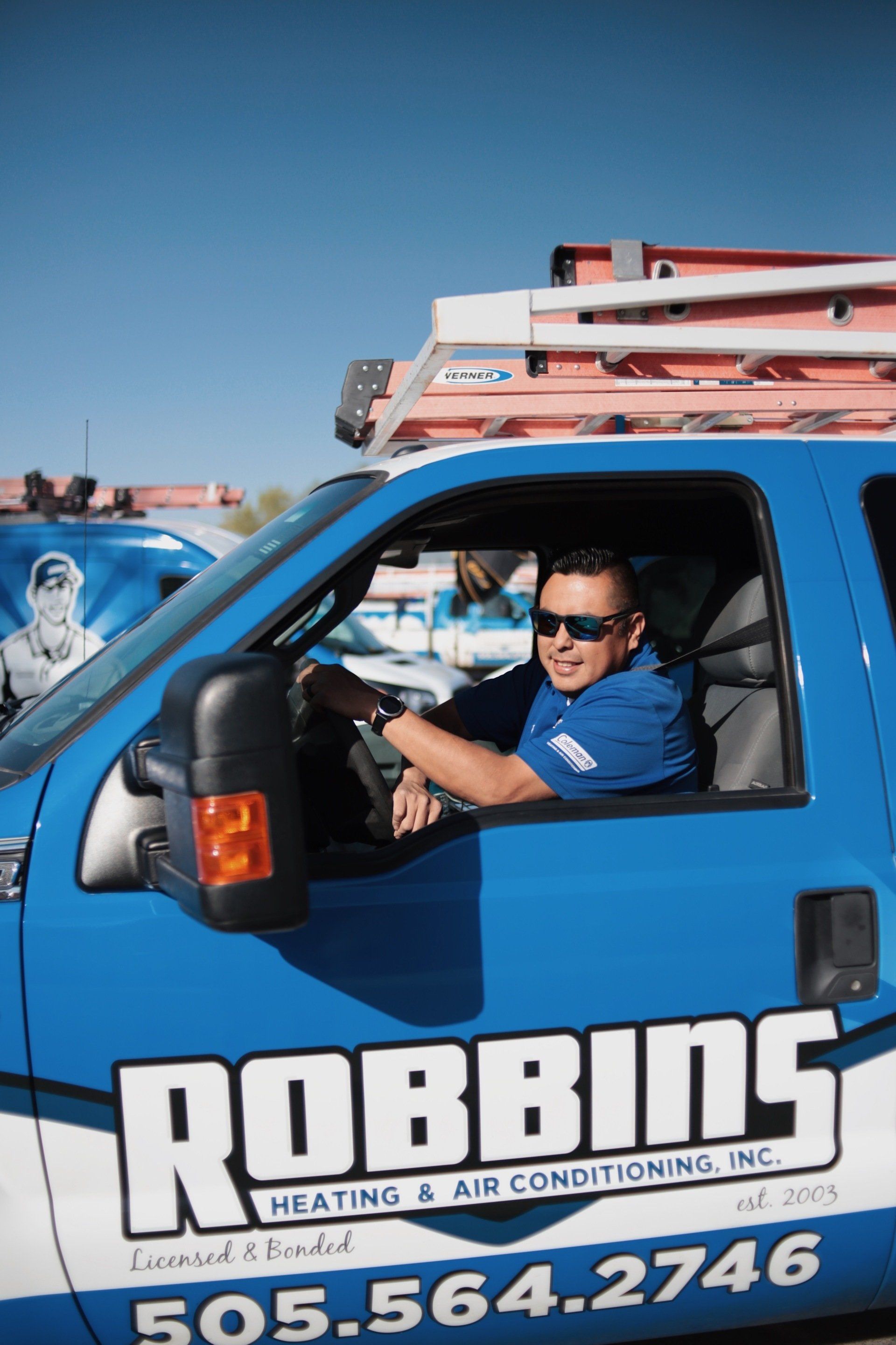 A man is sitting in the driver 's seat of a robbins heating and air conditioning truck.