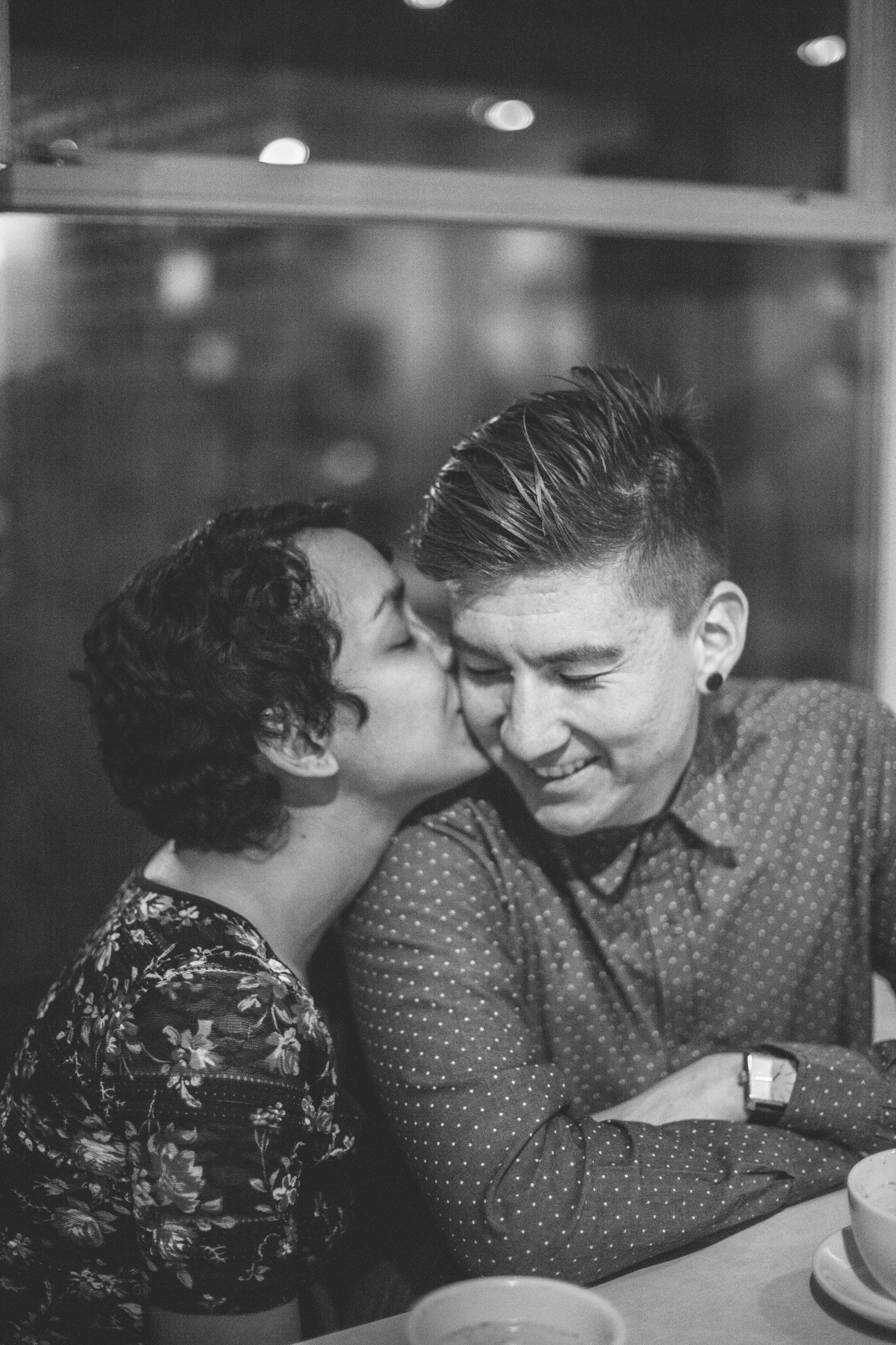 A woman is kissing a man on the cheek in a black and white photo.
