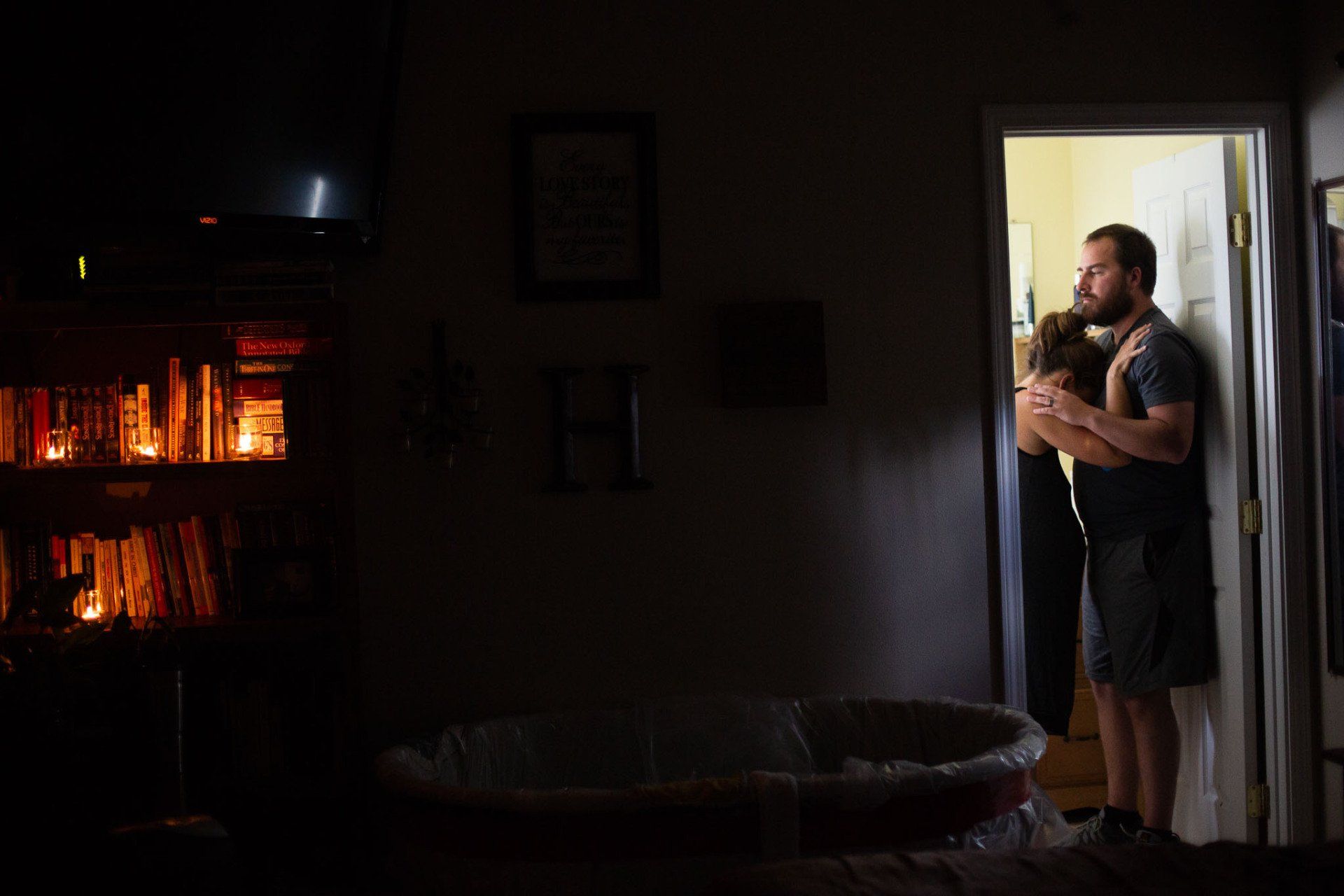 A man is holding a woman in his arms in a dark room.