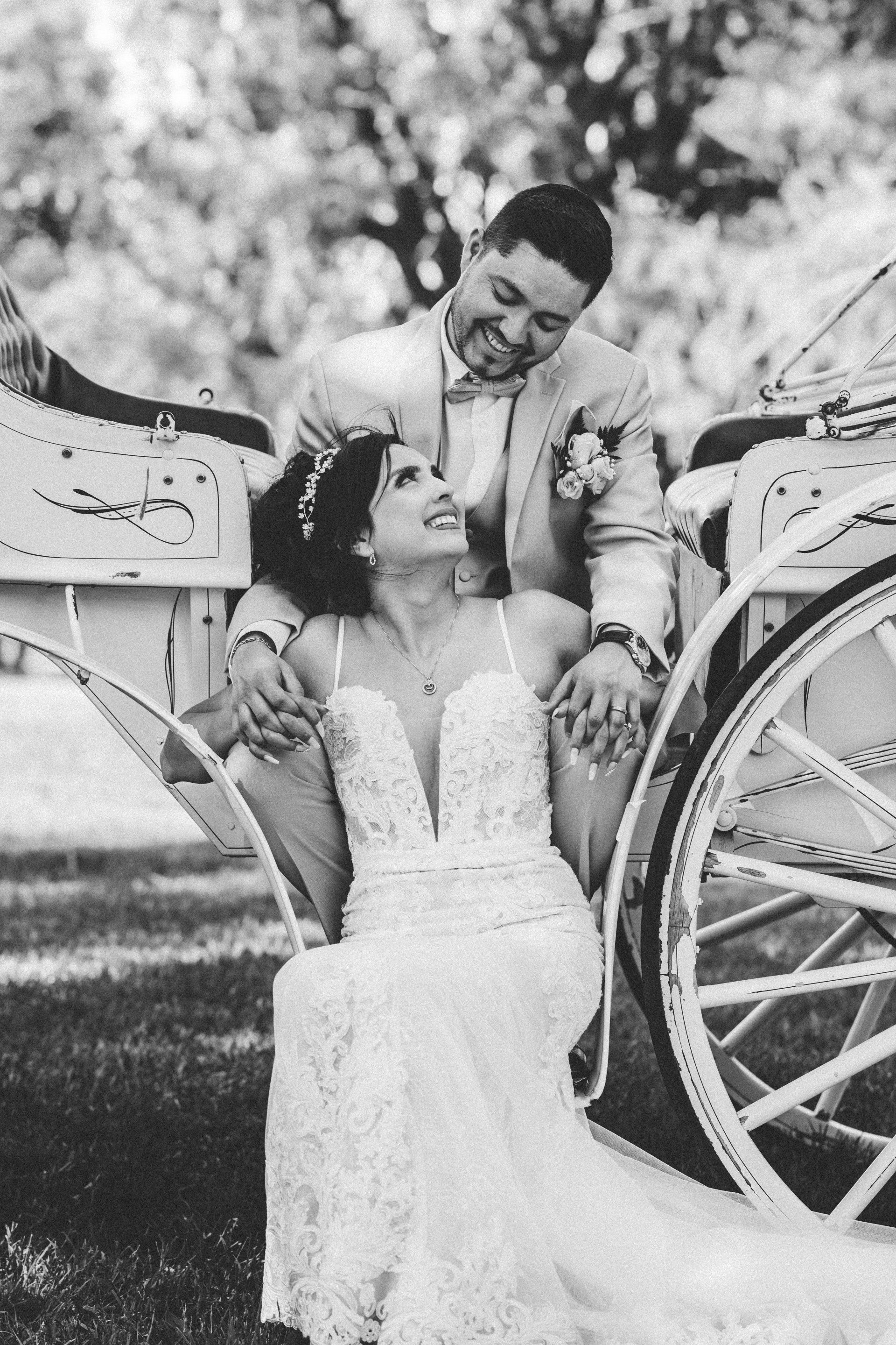 A bride and groom are sitting in a horse drawn carriage.
