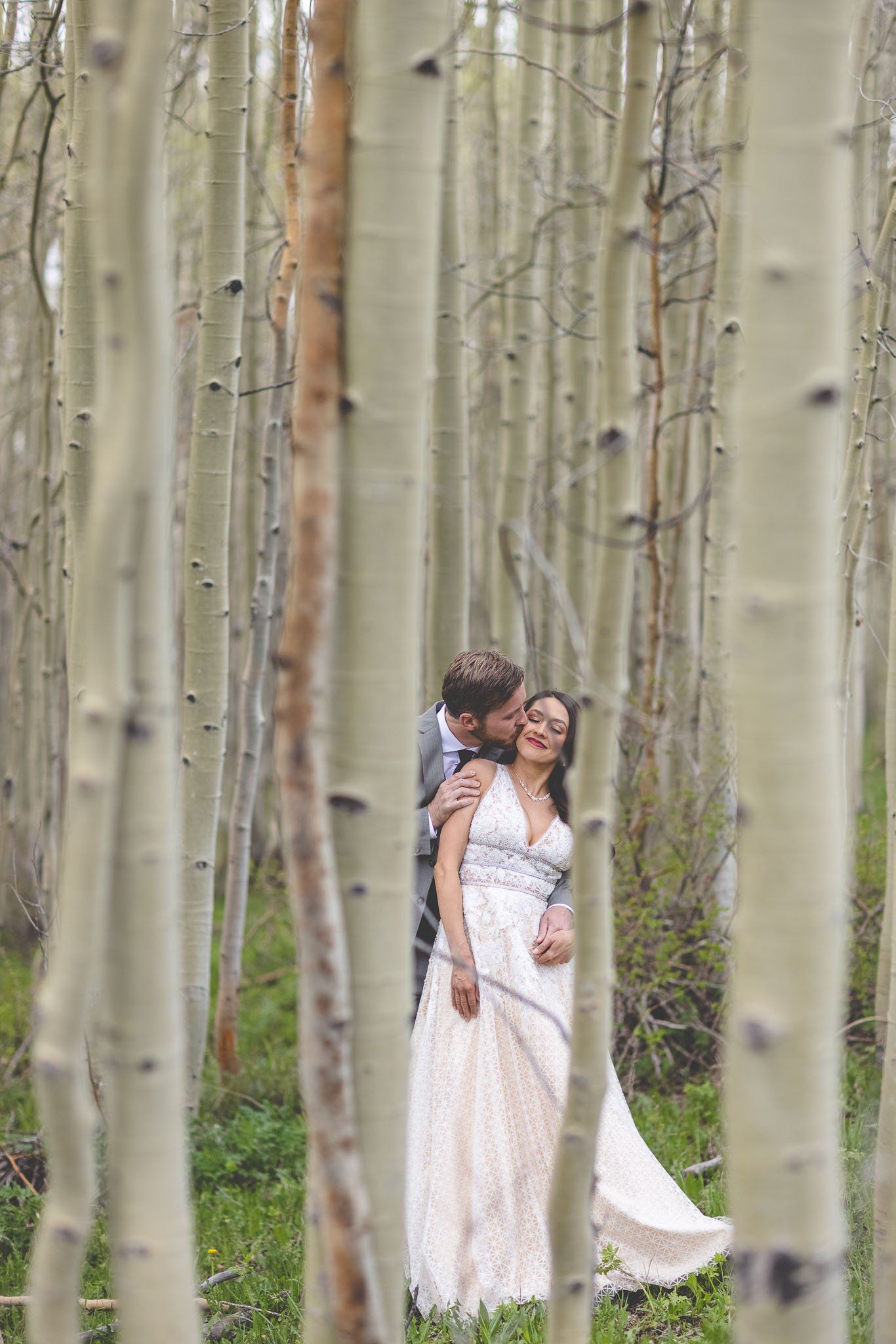 A bride and groom are posing for a picture in a forest.