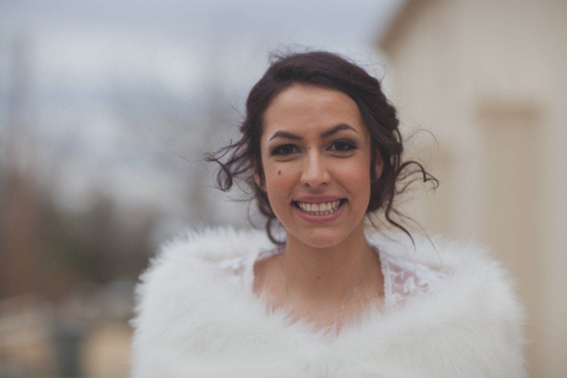 A woman in a white fur coat is smiling for the camera.