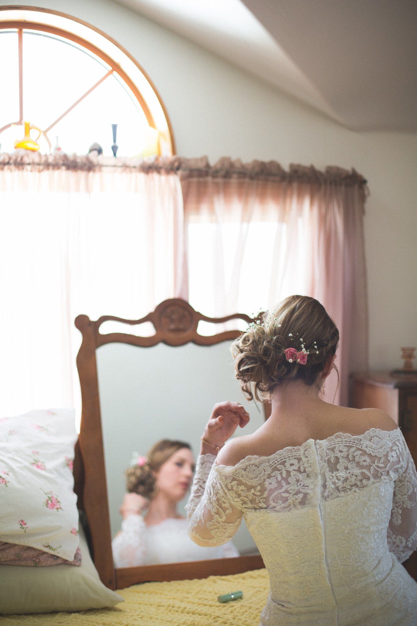 A woman in a wedding dress is looking at herself in a mirror.