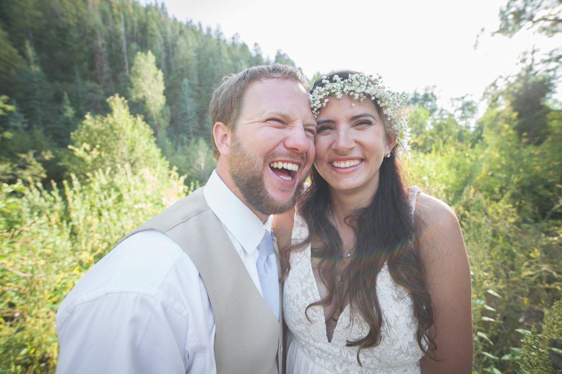 A bride and groom are laughing together in a field.