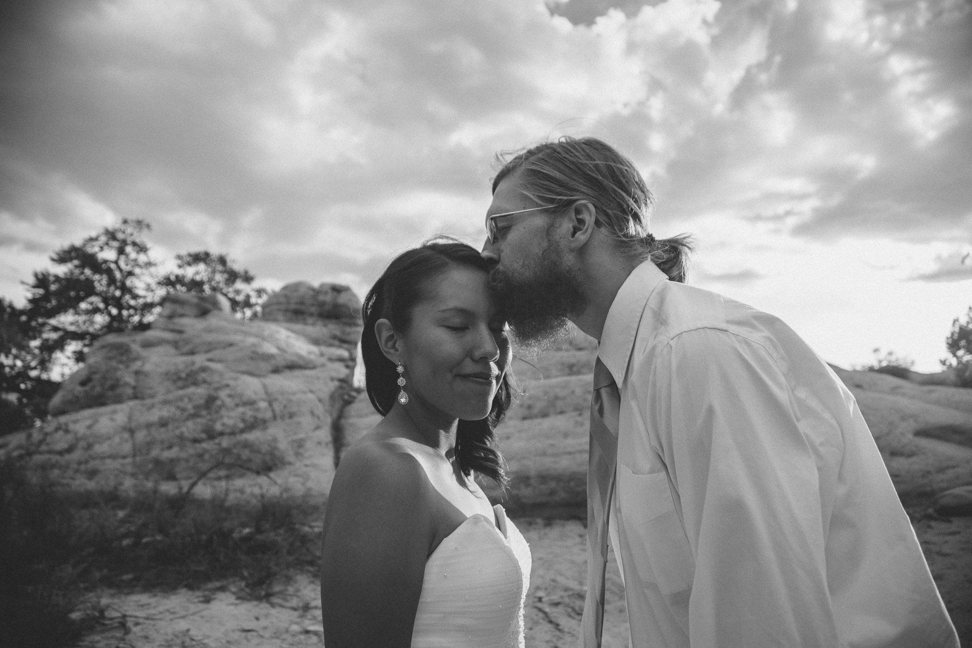 A man is kissing a woman on the forehead in a black and white photo.