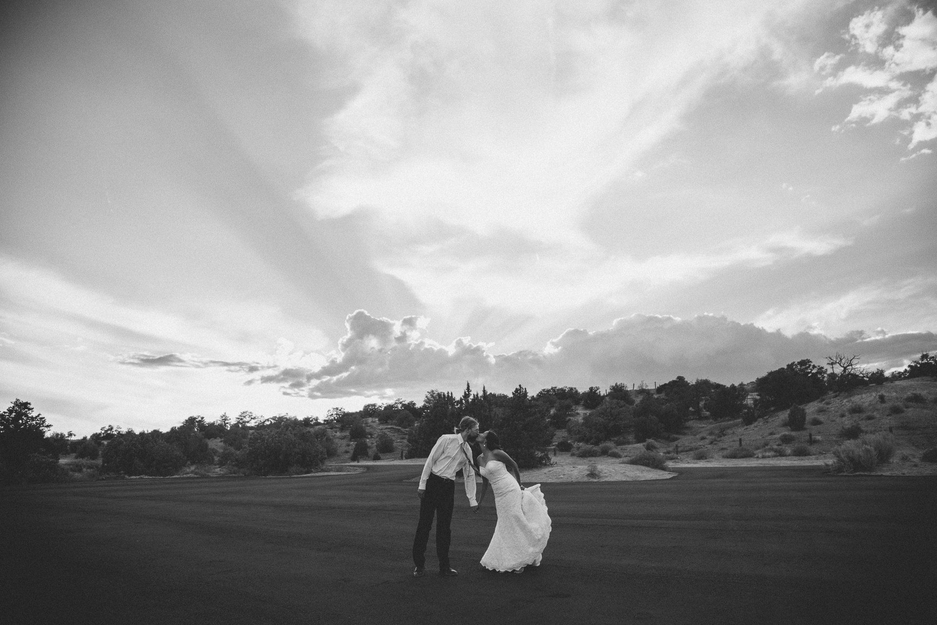 A black and white photo of a bride and groom dancing in a field.