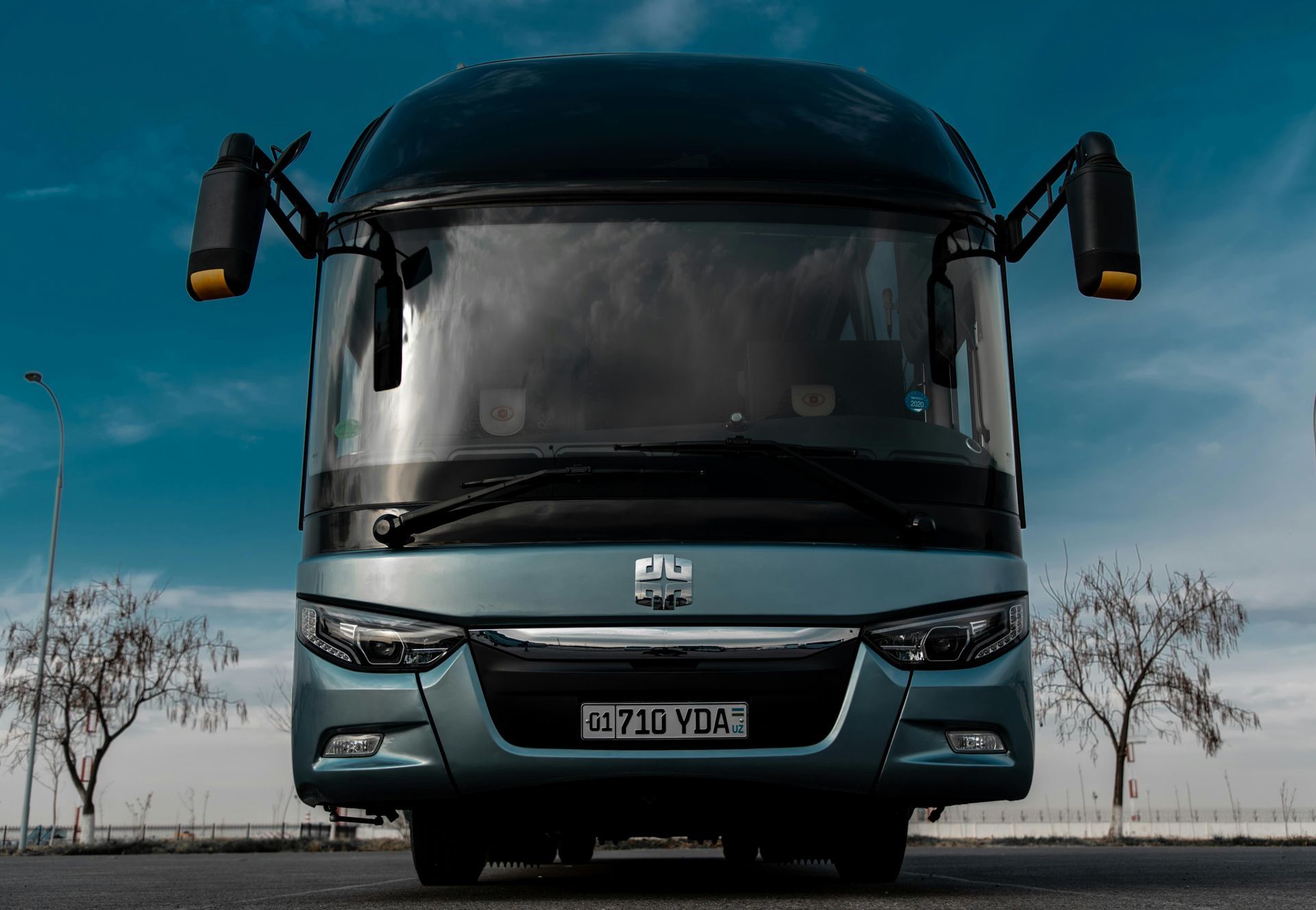 A black bus is driving down a curvy road.