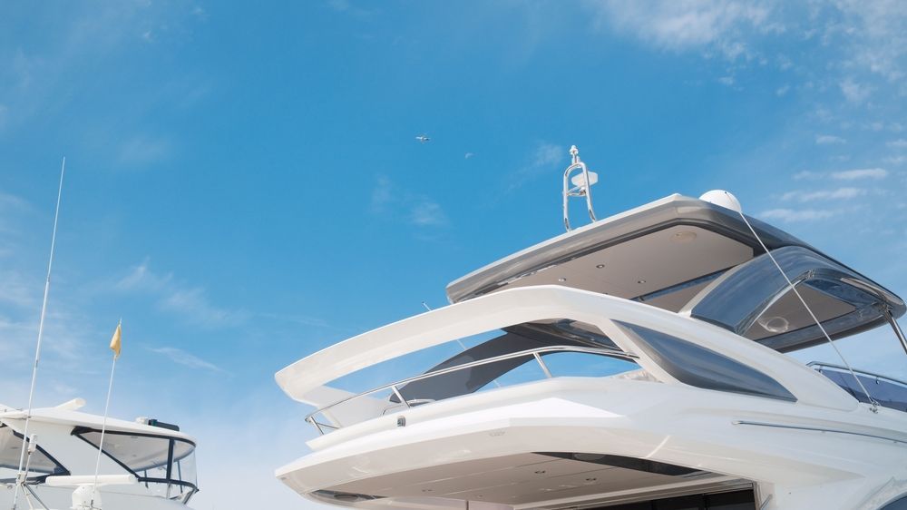 A white yacht is docked in the water with a blue sky in the background.