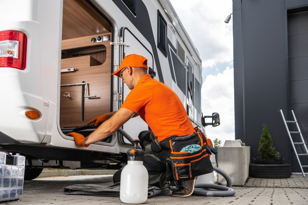 A man is cleaning a rv with a vacuum cleaner.