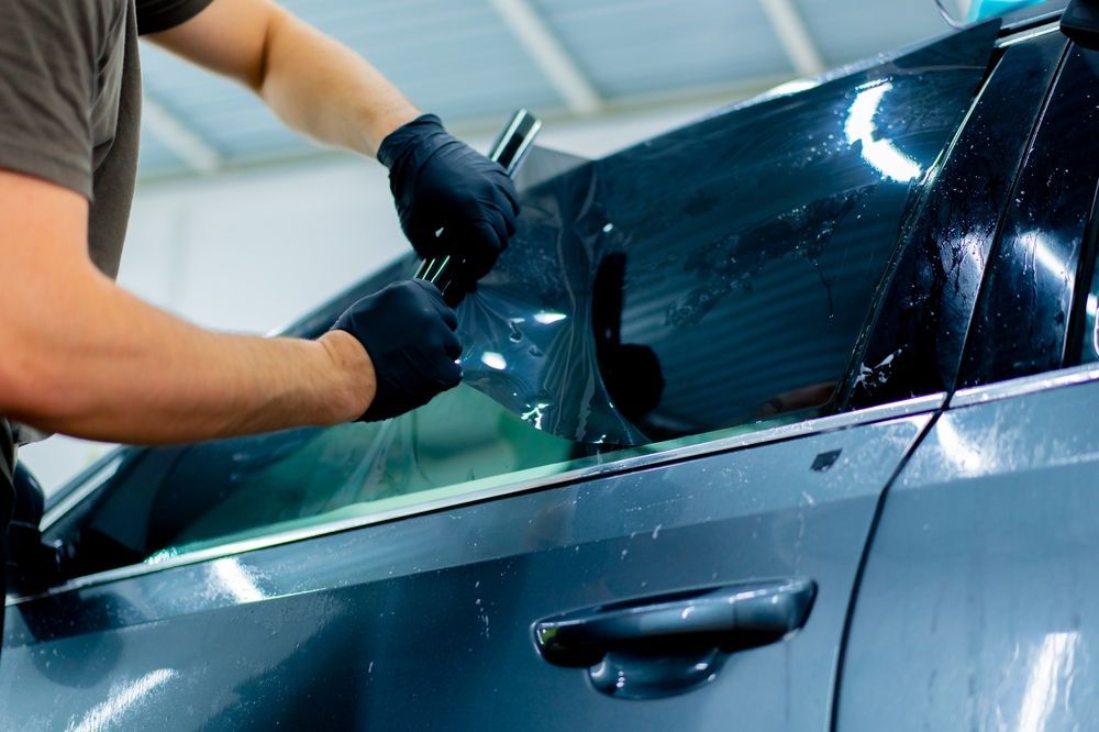 A man is applying tinted glass to a car window.