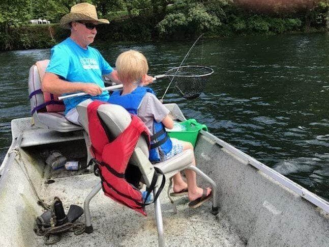 Rodney helping  a young boy by netting in a trout