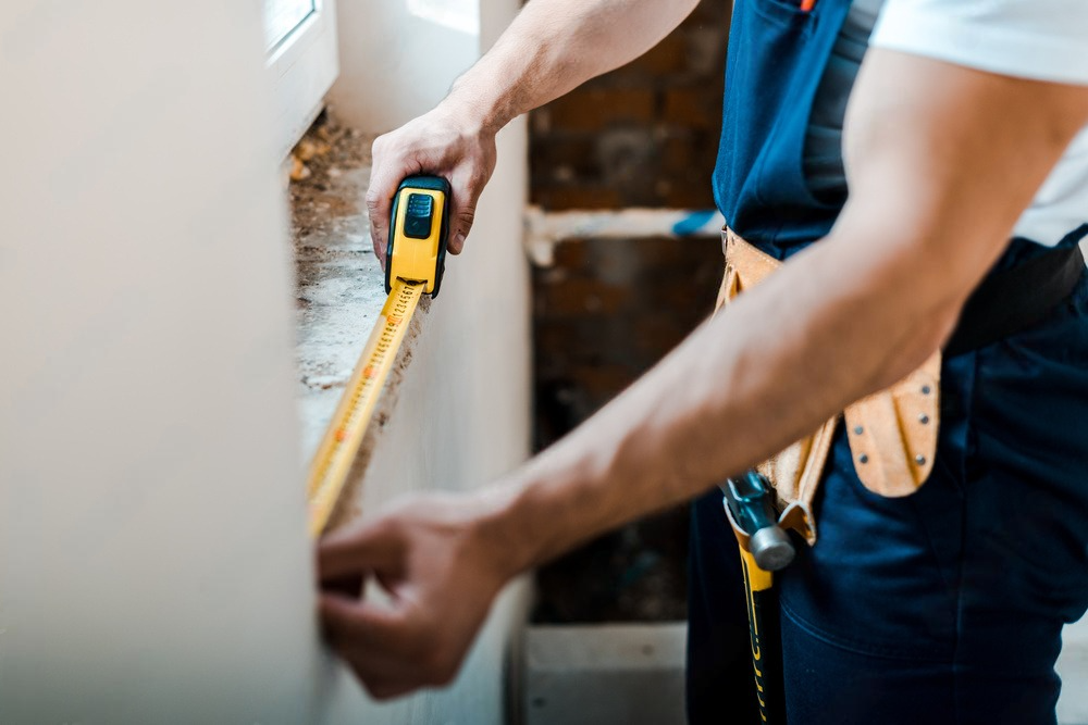 a man is measuring a wall with a tape measure