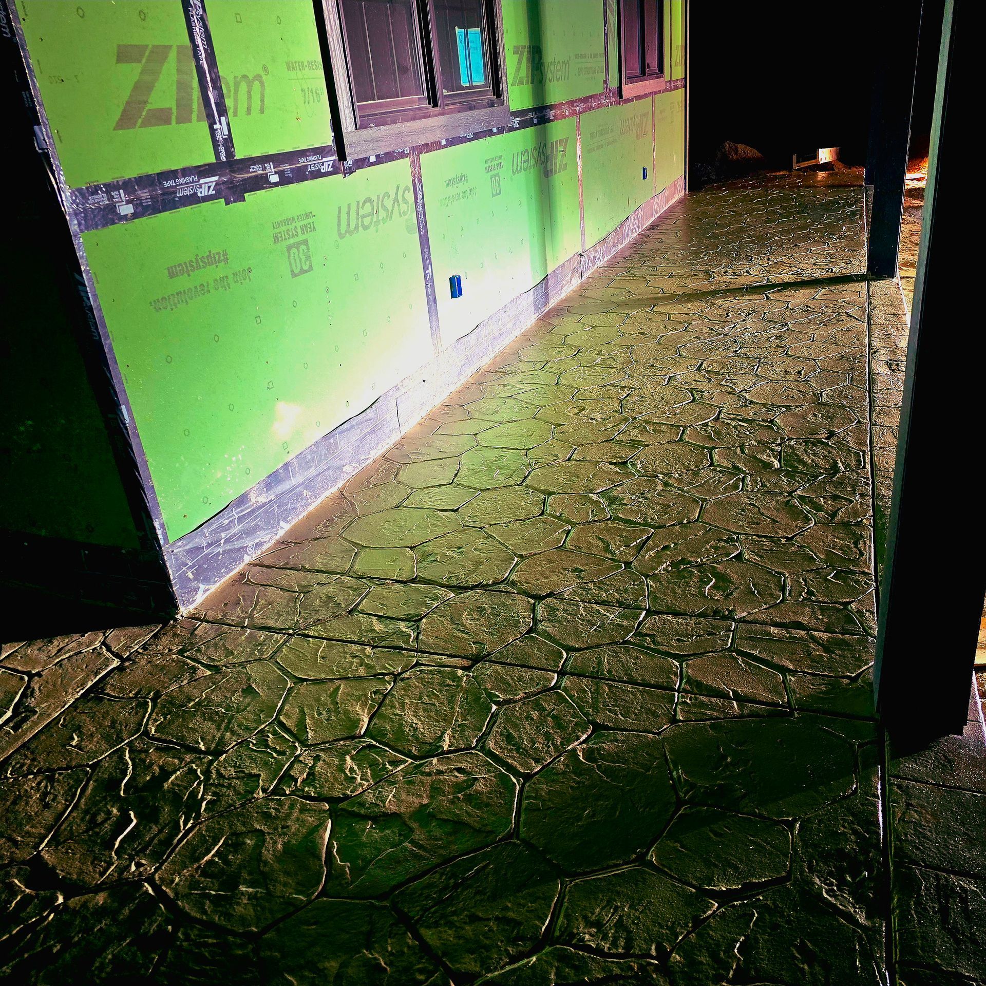 A hallway with a green wall and a concrete floor