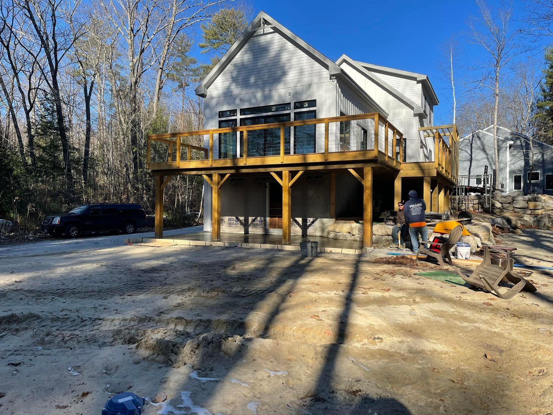 A house with a wooden deck is being built in the woods.