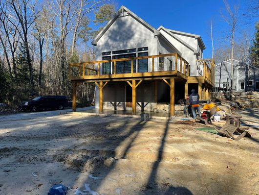 A house with a wooden deck is being built in the woods.