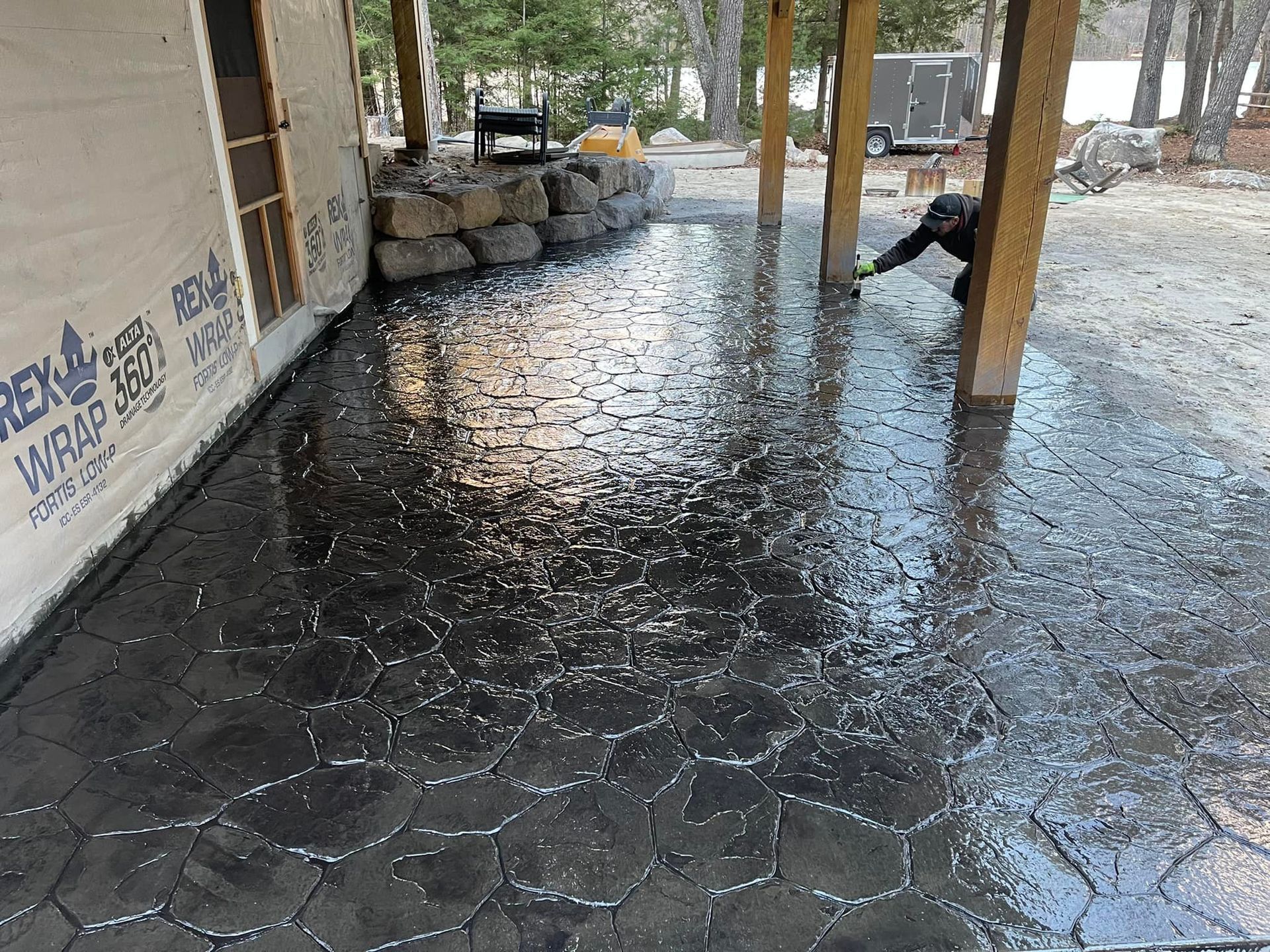 A person is working on a concrete patio under a covered porch.