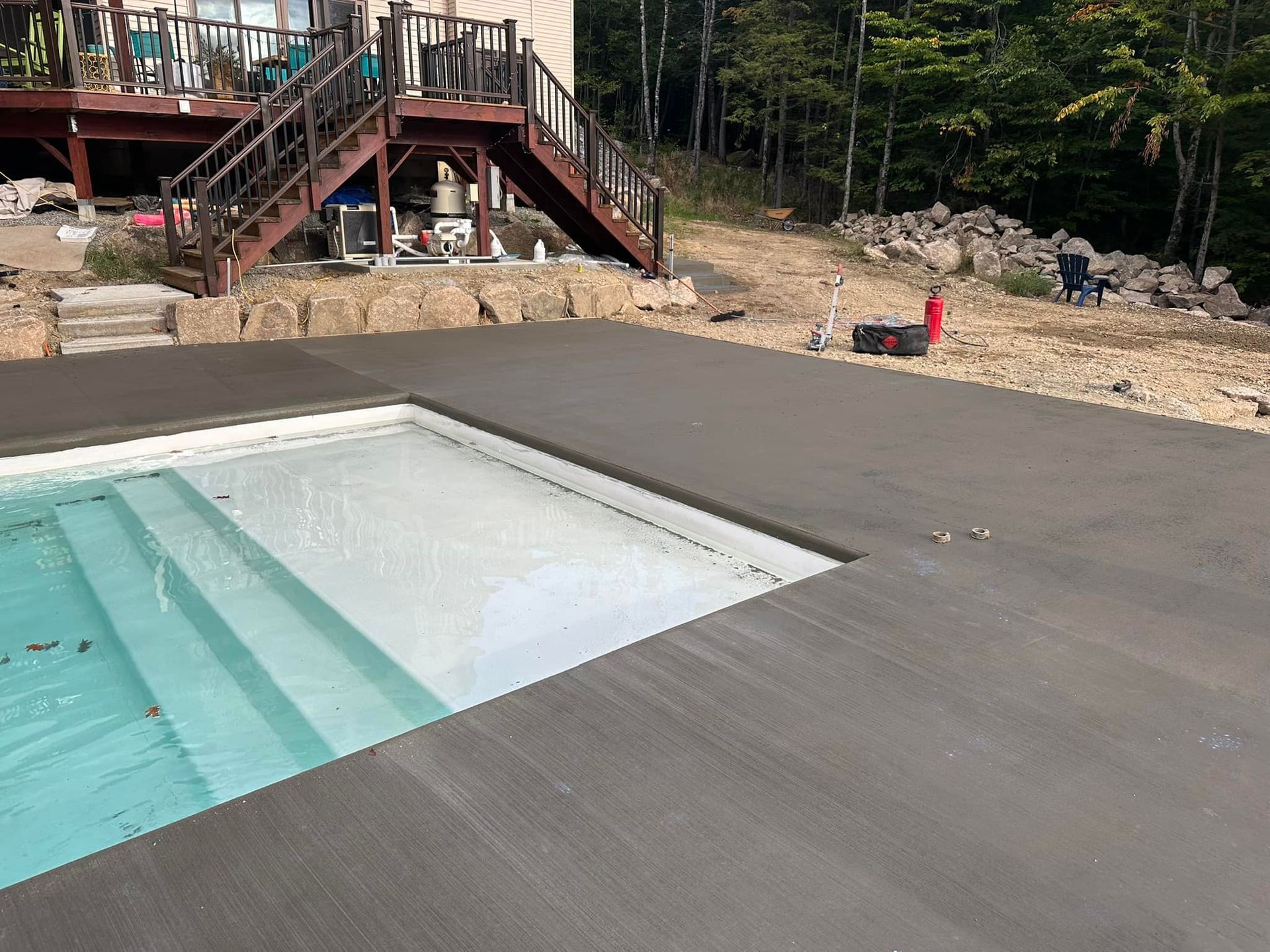 A swimming pool with stairs and a deck in the background.