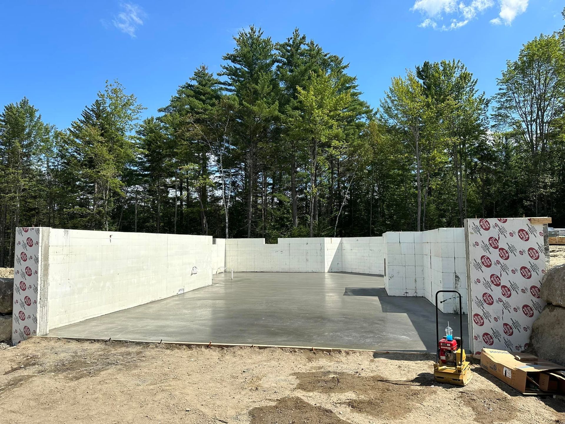 A concrete floor is being built in a yard with trees in the background