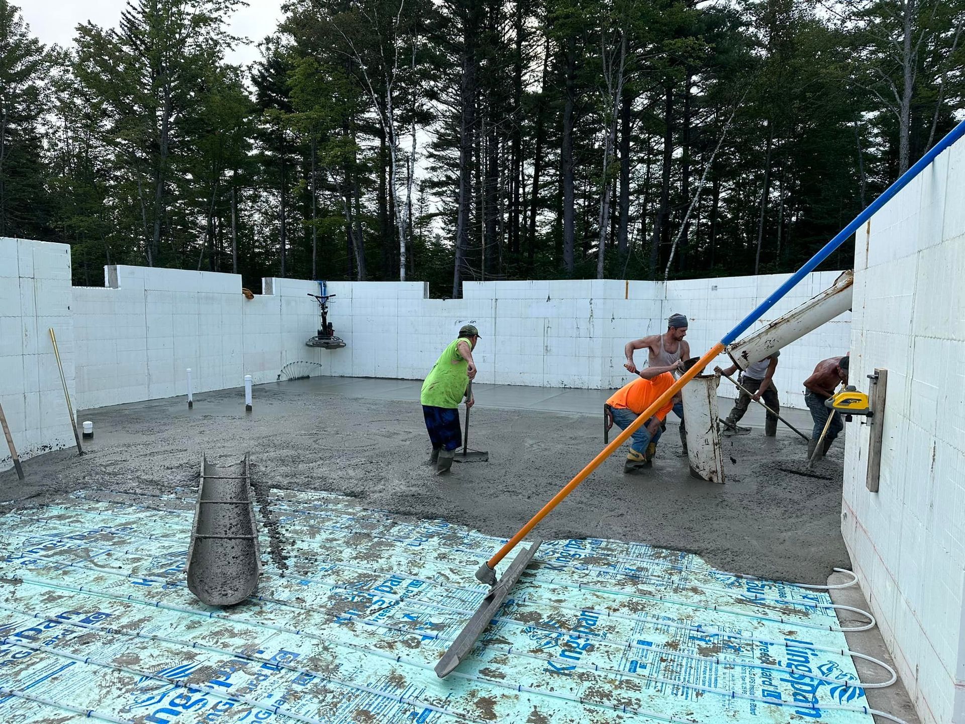 A group of construction workers are working on a concrete floor.