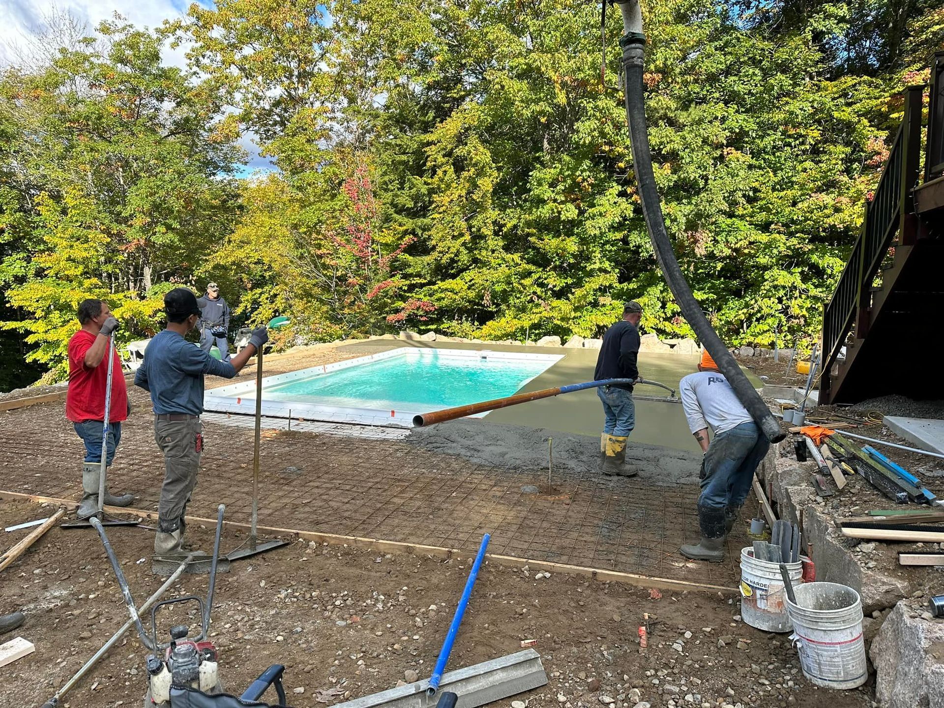 A group of construction workers are working on a swimming pool.