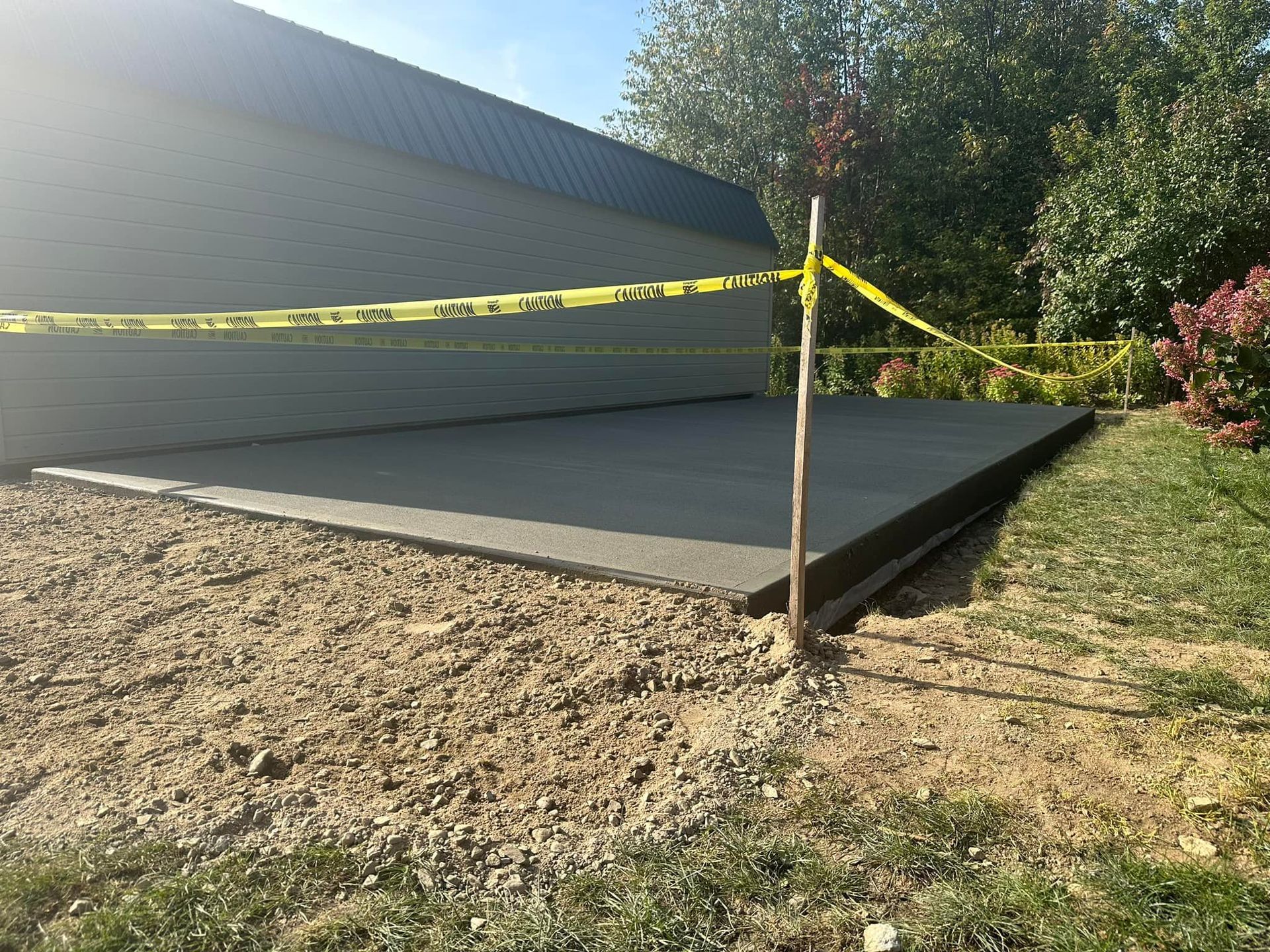 A concrete driveway is being built in front of a garage.