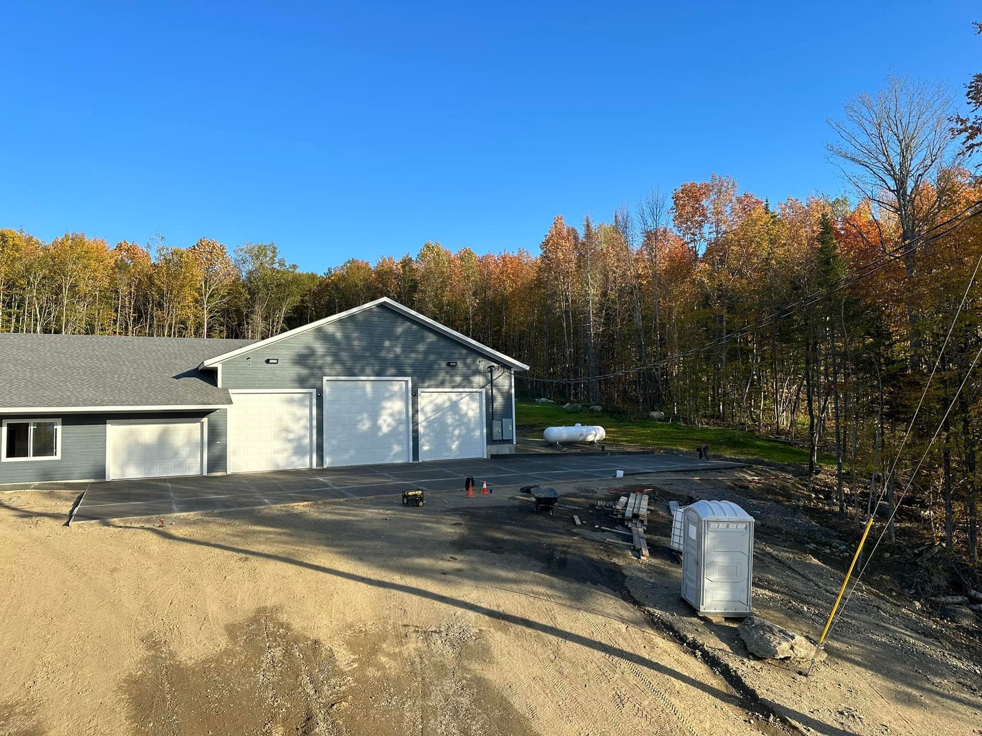 A house with two garage doors is sitting on top of a dirt hill.