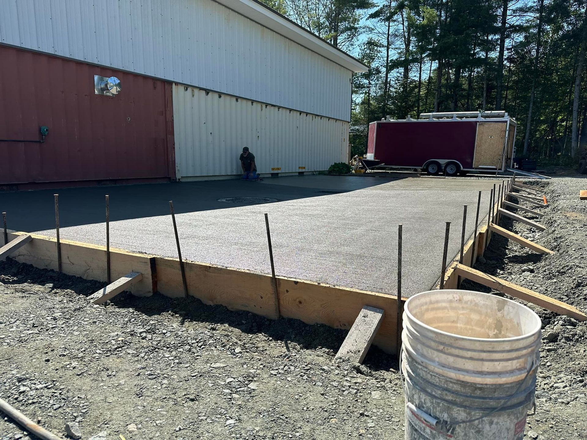 A bucket is sitting on the ground in front of a building under construction.
