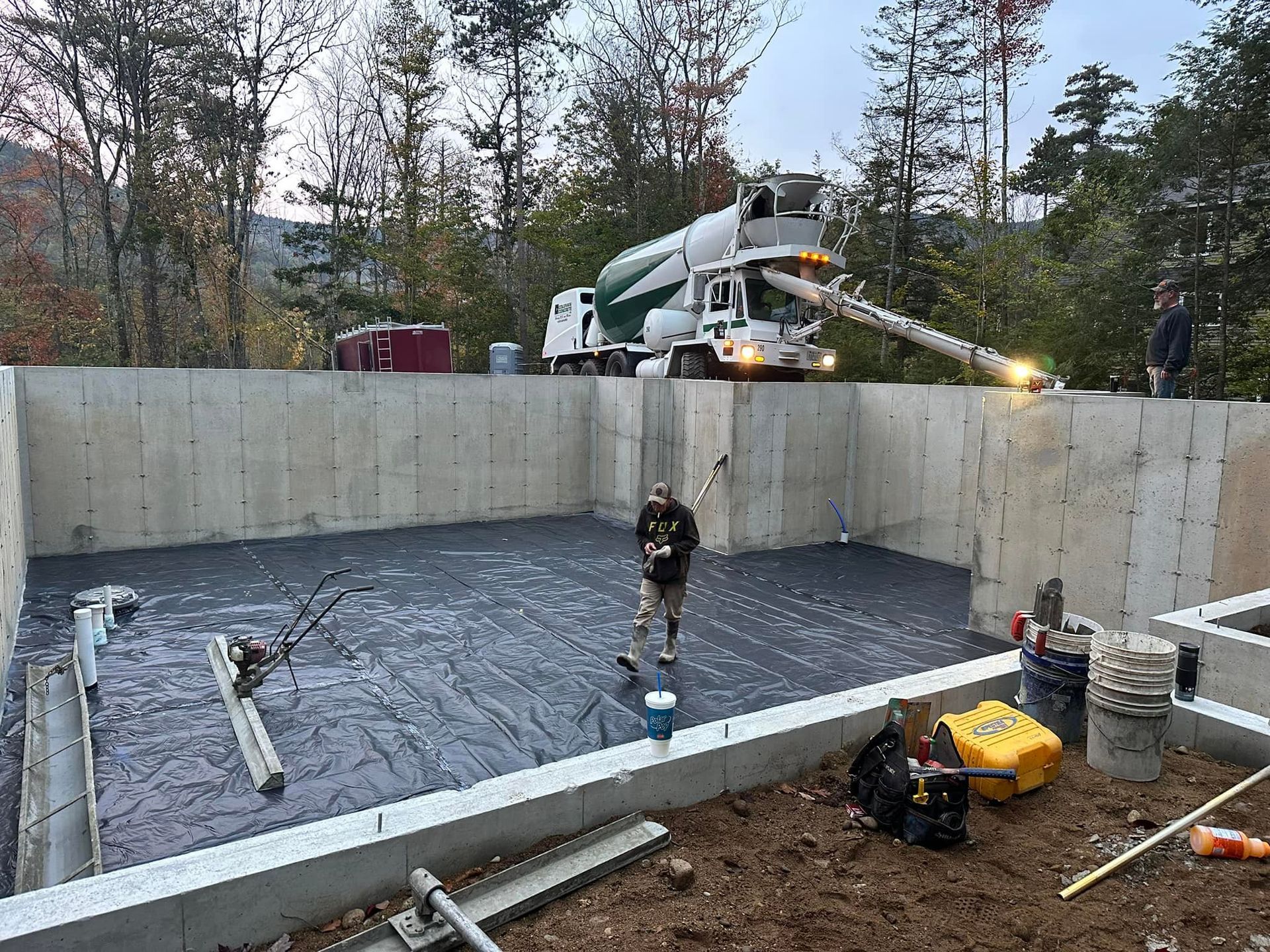 A concrete truck is pouring concrete into a foundation.