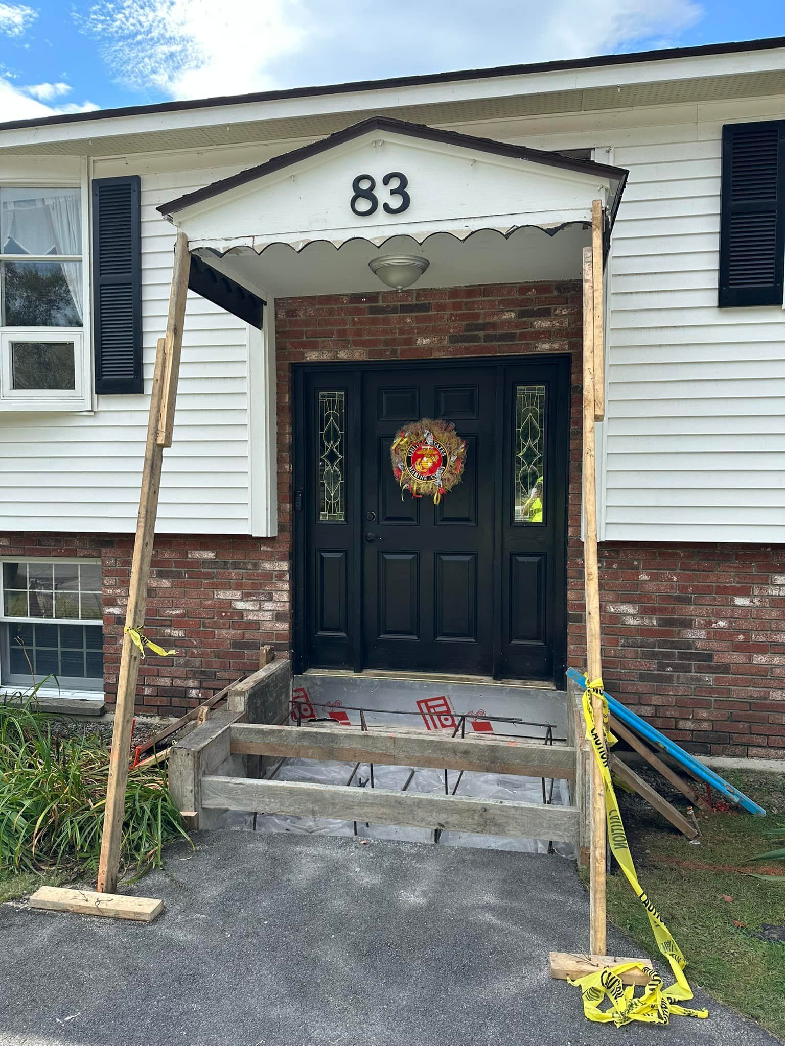 The front door of a house with a black door and a wreath on it.