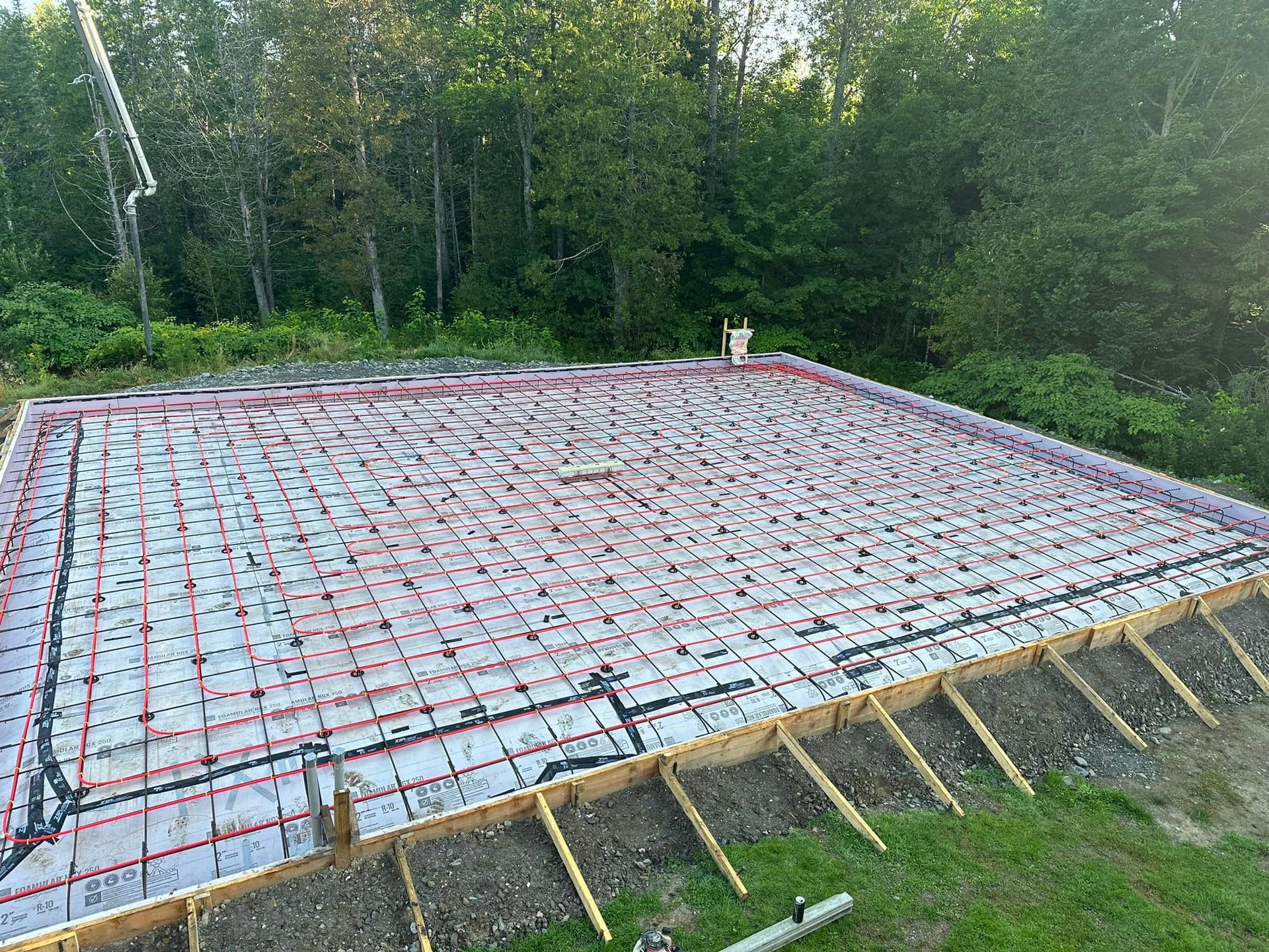 A concrete foundation is being built in a yard with trees in the background.