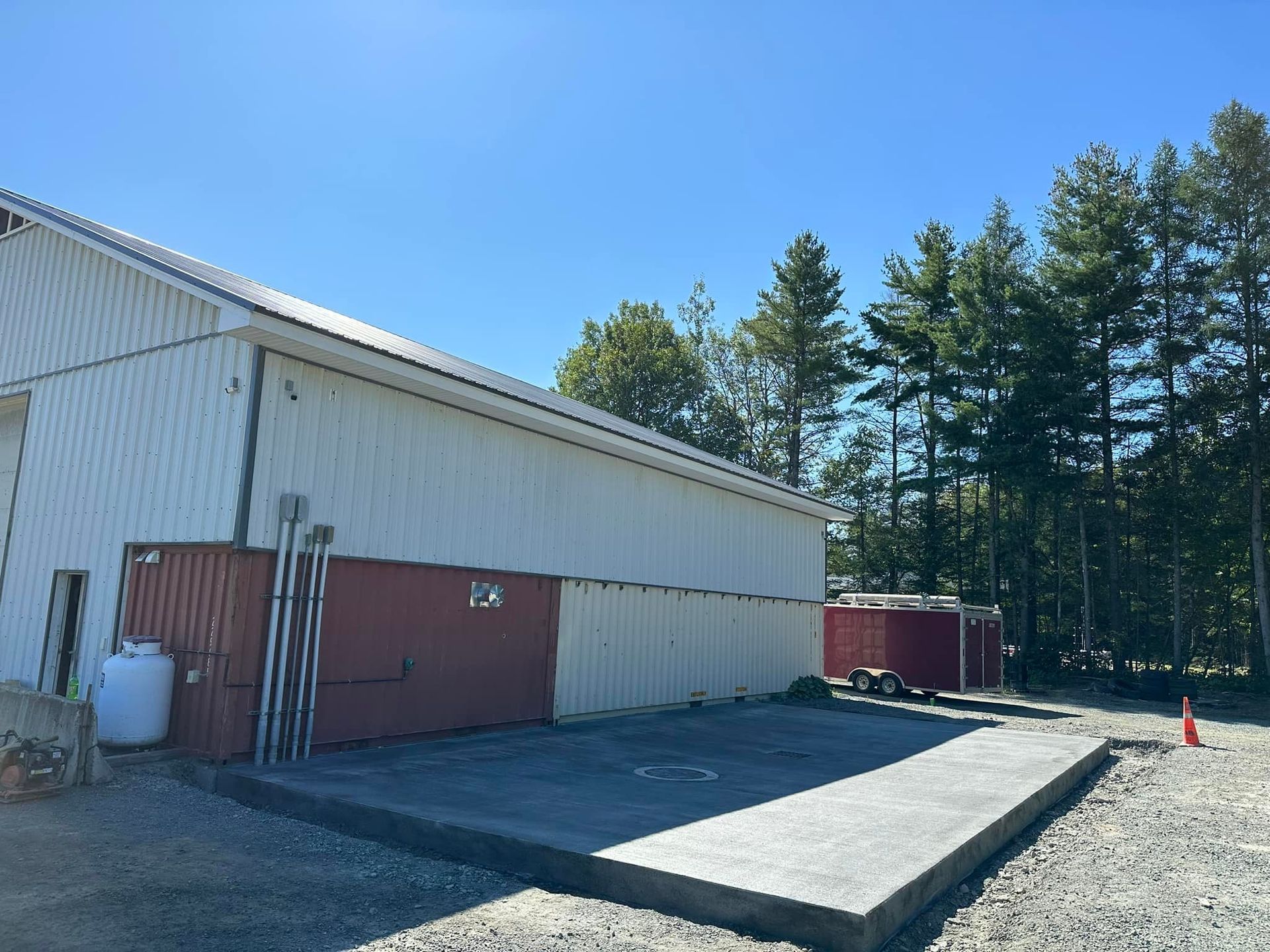 A white building with a red door is surrounded by trees