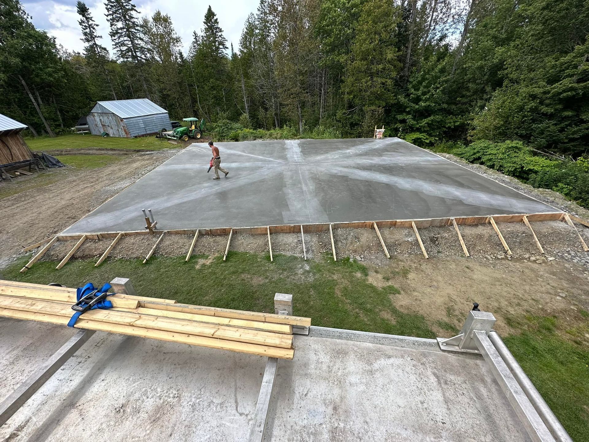 A man is walking on a concrete surface in a yard.