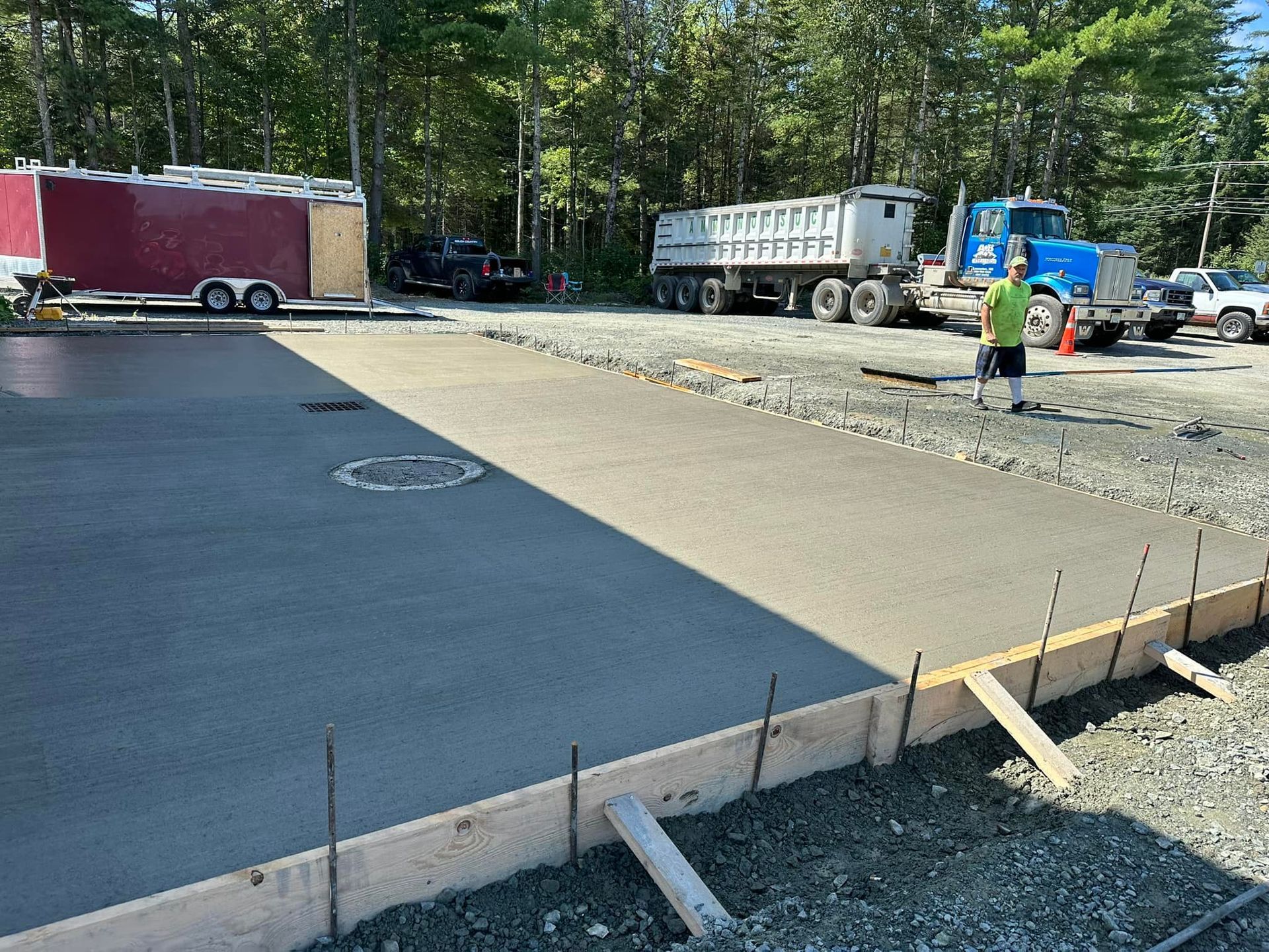 A man is standing in a parking lot next to a dump truck.